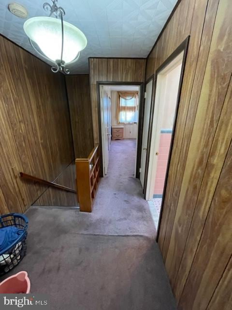 hallway with carpet flooring and wooden walls