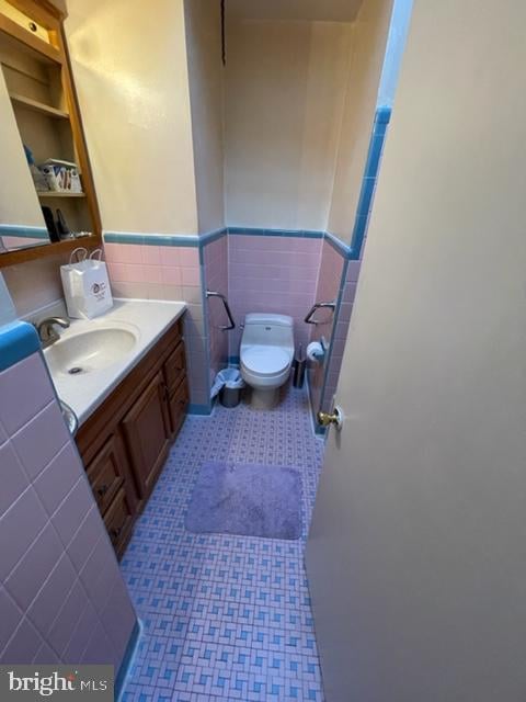 bathroom featuring vanity, toilet, and tile walls