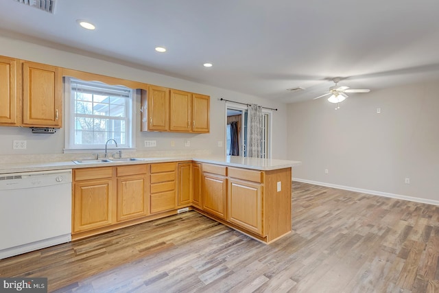 kitchen with kitchen peninsula, light wood-type flooring, white dishwasher, and sink