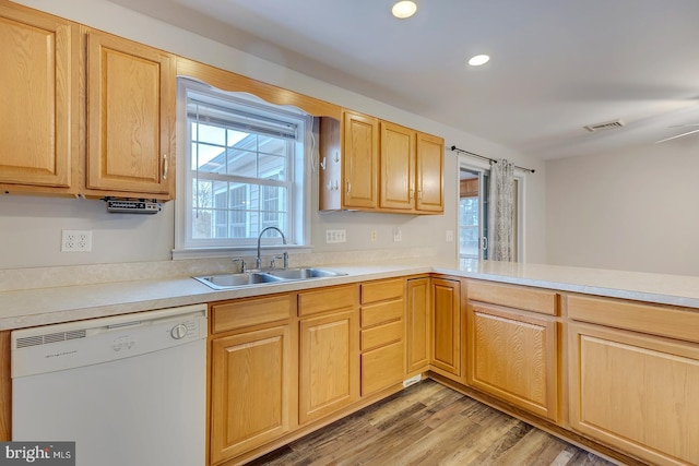 kitchen with sink, kitchen peninsula, white dishwasher, light brown cabinetry, and light wood-type flooring