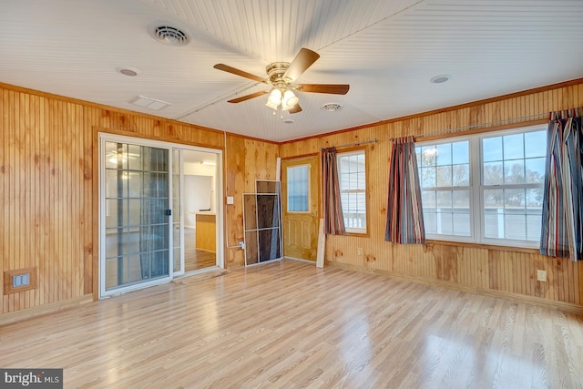 spare room with ornamental molding, light wood-type flooring, ceiling fan, and wooden walls