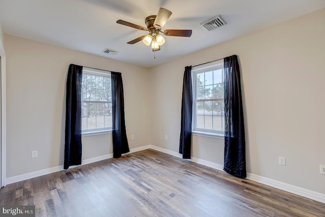 empty room with a wealth of natural light, hardwood / wood-style floors, and ceiling fan