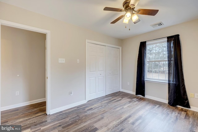 unfurnished bedroom with ceiling fan, wood-type flooring, and a closet