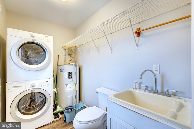 laundry area with sink, stacked washer and dryer, hardwood / wood-style flooring, and water heater