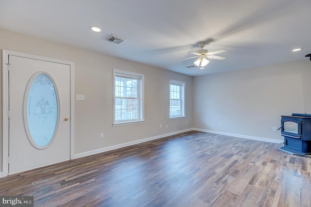 entrance foyer featuring ceiling fan, a wood stove, and dark wood-type flooring