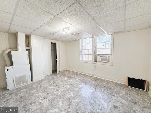 basement featuring a drop ceiling, cooling unit, and heating unit