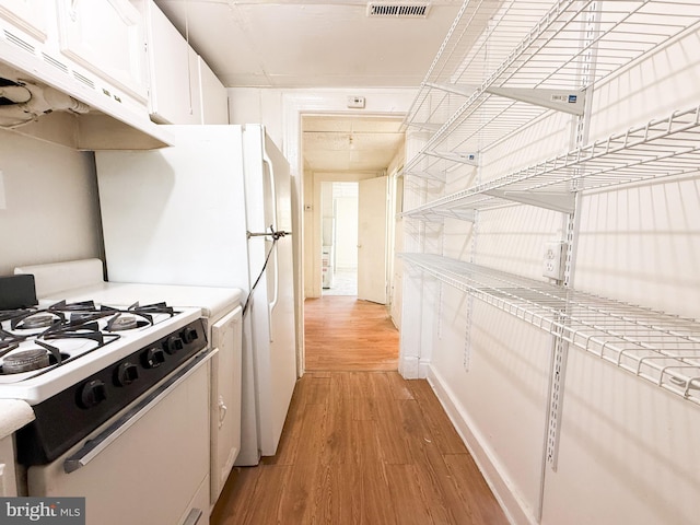 kitchen with white cabinets, light hardwood / wood-style floors, and white gas range oven