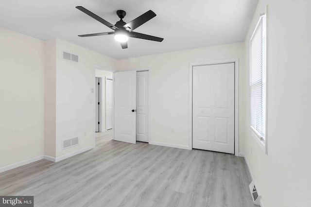 unfurnished bedroom with multiple closets, ceiling fan, and light hardwood / wood-style floors