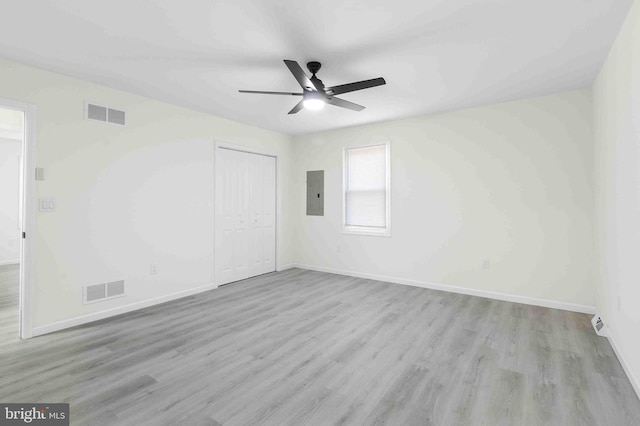 unfurnished bedroom with ceiling fan, light wood-type flooring, electric panel, and a closet