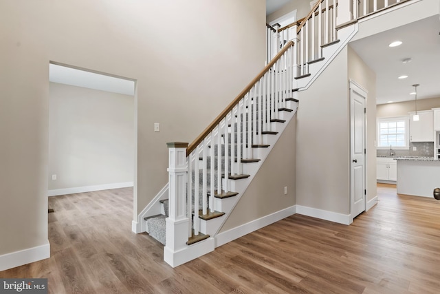 staircase with recessed lighting, wood finished floors, and baseboards