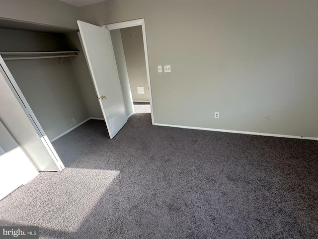 unfurnished bedroom featuring dark colored carpet and a closet