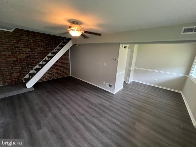 unfurnished living room featuring a textured ceiling, brick wall, and dark hardwood / wood-style floors