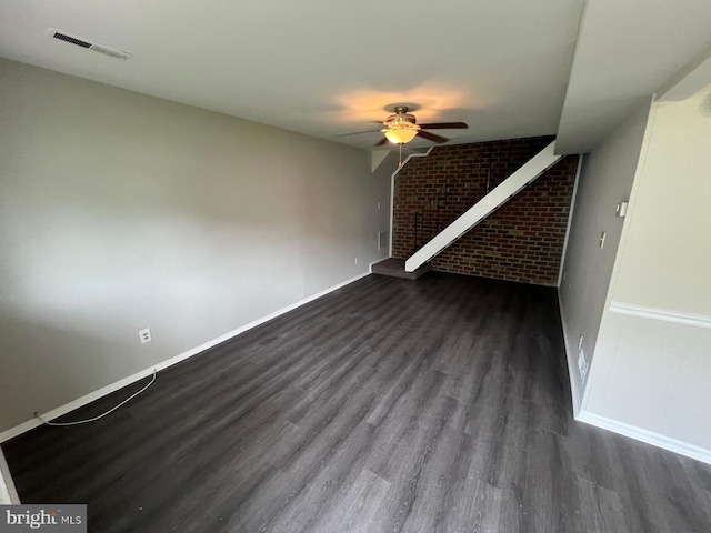 interior space featuring ceiling fan, brick wall, and dark hardwood / wood-style floors