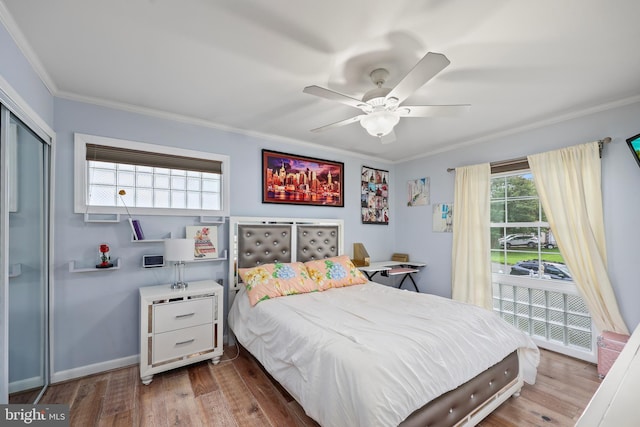 bedroom featuring multiple windows, ceiling fan, crown molding, and wood-type flooring