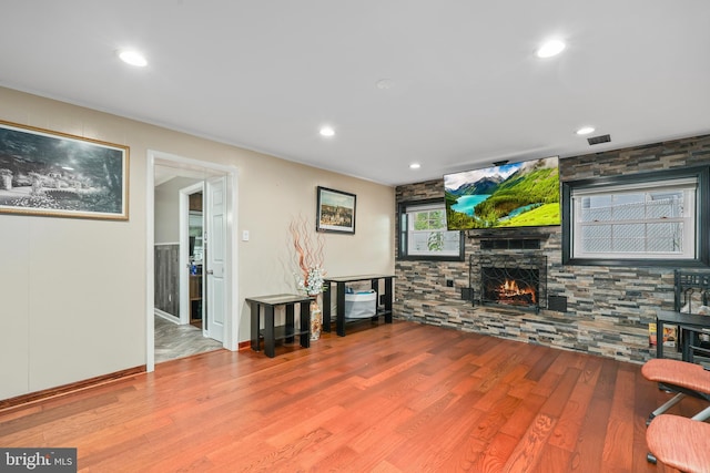 living room featuring light wood-type flooring and a stone fireplace