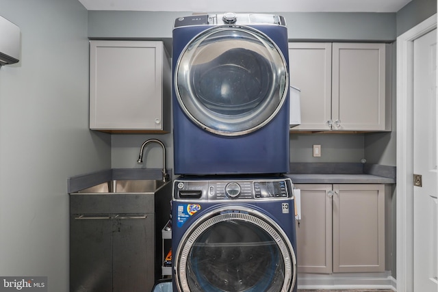 clothes washing area featuring cabinets, stacked washer / dryer, and sink