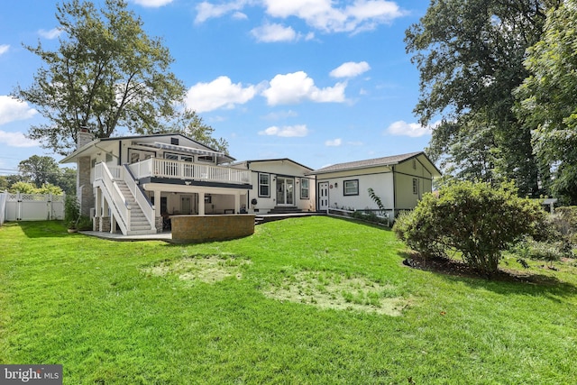 rear view of property featuring a lawn, a deck, and a patio