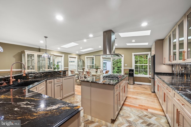 kitchen with pendant lighting, sink, dark stone countertops, light wood-type flooring, and island range hood