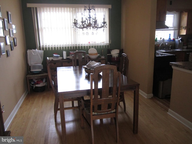 dining area featuring wood-type flooring, a notable chandelier, and sink