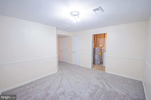 spare room with light carpet and water heater