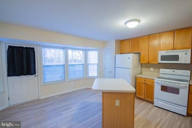 kitchen featuring light hardwood / wood-style flooring, a kitchen island, and white appliances