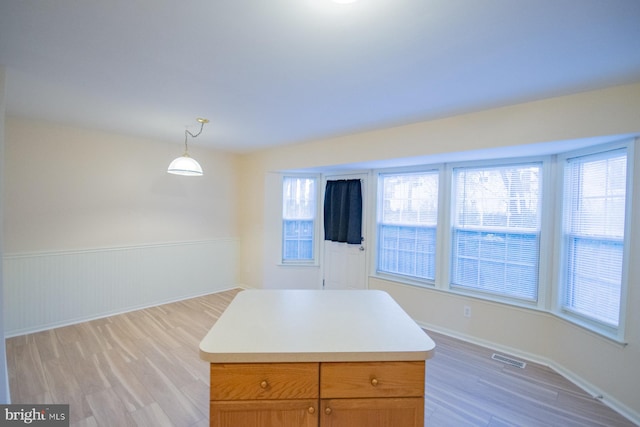 kitchen featuring decorative light fixtures, a center island, and light hardwood / wood-style flooring