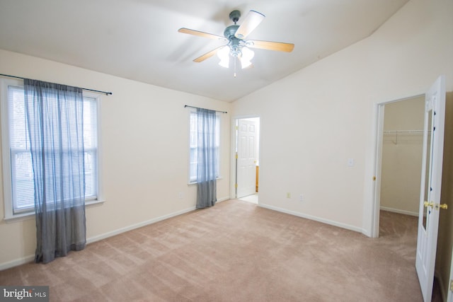 carpeted spare room featuring ceiling fan, lofted ceiling, and a wealth of natural light