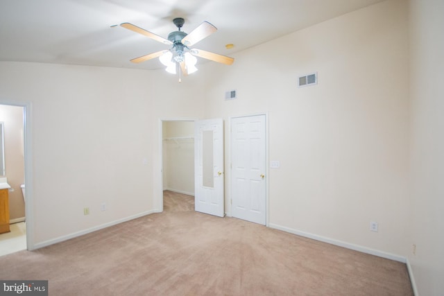 unfurnished bedroom with ceiling fan, high vaulted ceiling, light colored carpet, and a spacious closet