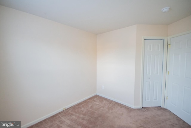 unfurnished bedroom featuring light carpet and a closet