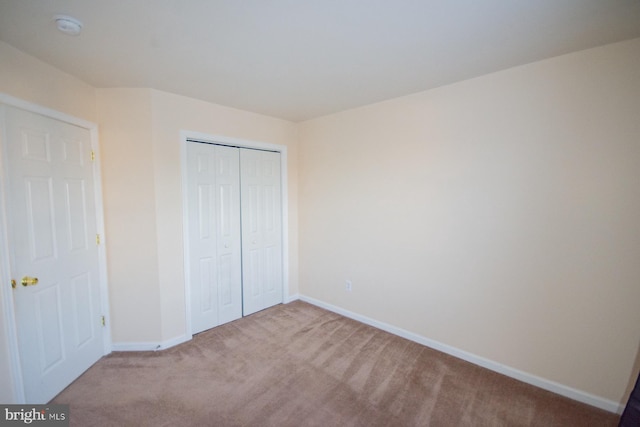 unfurnished bedroom with light carpet and a closet