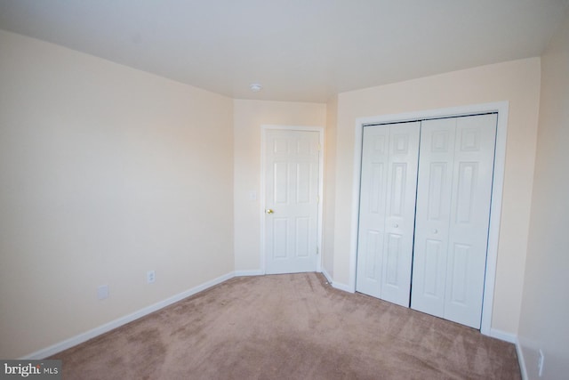 unfurnished bedroom featuring light colored carpet and a closet