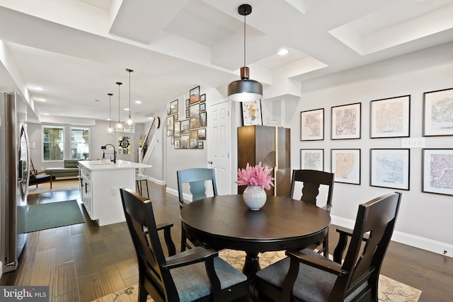 dining space with dark hardwood / wood-style flooring, sink, and coffered ceiling