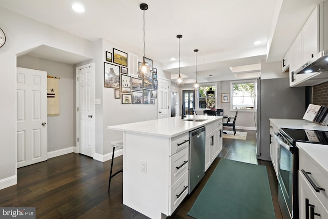 kitchen featuring stainless steel appliances, a kitchen island with sink, sink, pendant lighting, and white cabinetry