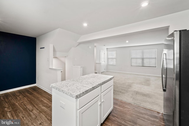 kitchen with dark carpet, stainless steel fridge, a center island, and white cabinetry