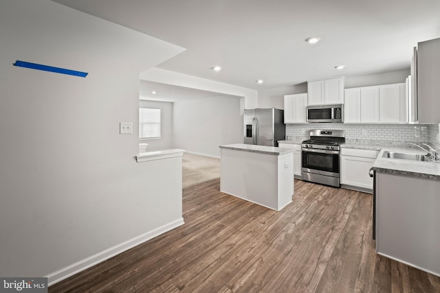 kitchen with a center island, sink, white cabinetry, wood-type flooring, and stainless steel appliances