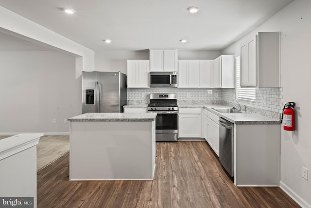 kitchen with white cabinetry, sink, stainless steel appliances, dark hardwood / wood-style floors, and a kitchen island