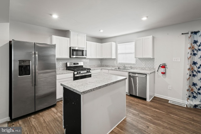 kitchen with white cabinets, dark hardwood / wood-style flooring, a kitchen island, and stainless steel appliances