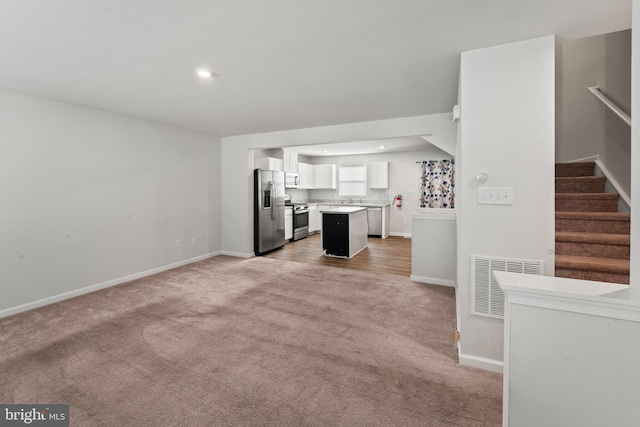 unfurnished living room with light colored carpet and sink