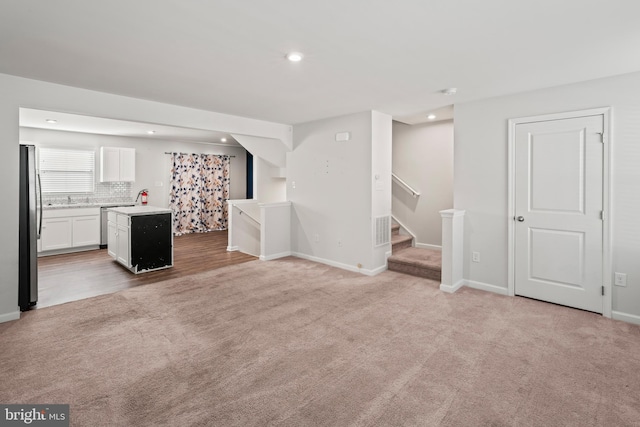 unfurnished living room with light colored carpet and sink