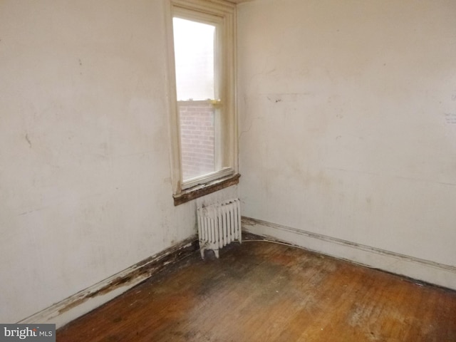 empty room with dark hardwood / wood-style flooring and radiator