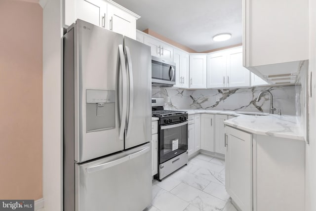 kitchen featuring white cabinets, decorative backsplash, stainless steel appliances, and sink