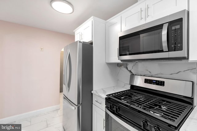 kitchen featuring decorative backsplash, light stone counters, white cabinetry, and appliances with stainless steel finishes