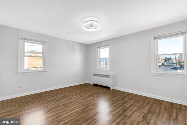 empty room featuring dark hardwood / wood-style floors and radiator heating unit