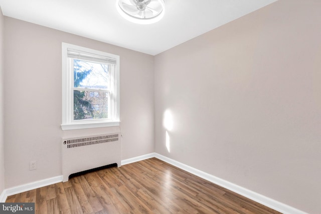 empty room featuring radiator and hardwood / wood-style floors