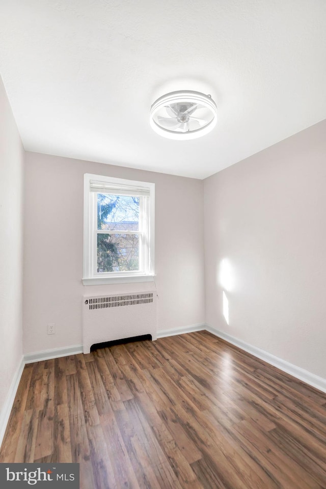 unfurnished room with ceiling fan, radiator heating unit, and dark hardwood / wood-style floors