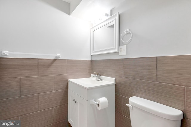 bathroom featuring vanity, toilet, and tile walls