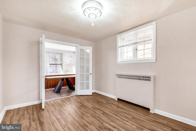 unfurnished dining area featuring a textured ceiling, light hardwood / wood-style flooring, and radiator