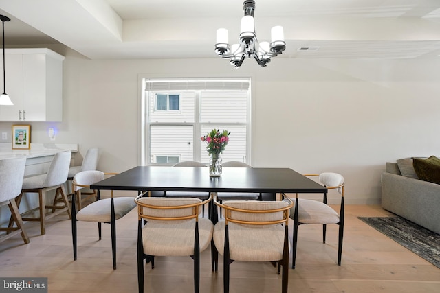 dining space with light wood finished floors, baseboards, visible vents, and a notable chandelier