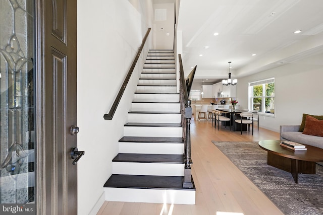 stairway featuring recessed lighting, a chandelier, and wood finished floors