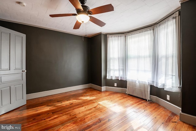 spare room featuring ceiling fan, radiator heating unit, ornamental molding, and light hardwood / wood-style flooring